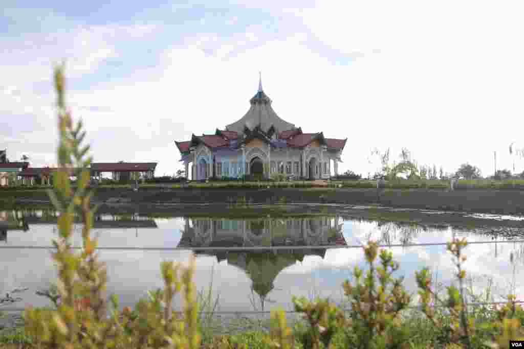 ត្រពាំងដែលមានរាងដូចផ្លិតត្រដាងនៅចំពីមុខទីសក្ការៈគោរពបូជា Baha'i ដែលមានជ្រុងប្រាំបួន តំណាងឲ្យសាមគ្គីភាពនៃសាសនាធំៗទាំងប្រាំបួនលើលោក។ វិហារនេះត្រូវបានកសាងតាមចក្ខុវិស័យស្របទៅនឹងសហគមន៍ ការរស់នៅ និងបរិស្ថានធម្មជាតិរបស់ខេត្តបាត់ដំបង។ (រិទ្ធី ឧត្តម/VOA)