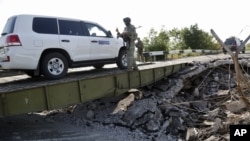 Mobil yang mengangkut tim forensik dan anggota OSCE dalam misi mereka di Ukraina melewati sebuah jembatan yang rusak di Debaltsevo, Ukraina timur (3/8/2014).