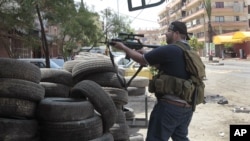 Milisi Sunni berlindung di balik ban-ban mobil dalam bentrokan antara pendukung dan penentang al-Assad di kota Tripoli, Libanon, (13/5).