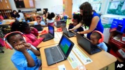 Second grade student Khalil Morgan, left, reacts after completing an interactive math problem on his computer, with teacher Jillian Martin, standing to the right, at Turner Elementary School in southeast Washington, Tuesday, Aug. 29, 2017. (AP Photo/Manue