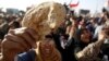 An Egyptian holds a piece of bread to protest against the high prices of goods in Tahrir Square in Cairo, February 8, 2013. 