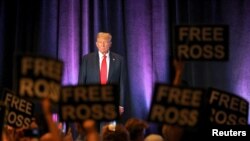La gente sostiene carteles en apoyo del encarcelado fundador del mercado de la red oscura Silk Road, Ross Ulbricht, mientras el expresidente de EEUU, Donald Trump, asiste a la convención nacional del Partido Libertario en Washington, el 25 de mayo de 2024.