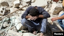 A man reacts on the rubble of damaged buildings after losing relatives to an airstrike in the besieged rebel-held al-Qaterji neighborhood of Aleppo, Syria, Oct. 11, 2016.