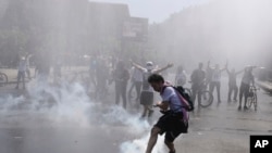A protester kicks a tear gas canister during clashes with police in Santiago, Chile, Oct. 20, 2019.