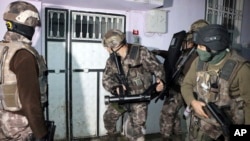 Turkish anti-terrorism police break a door during an operation to arrest people over alleged links to the Islamic State group, in Adiyaman, southeastern Turkey, Feb. 5, 2017.