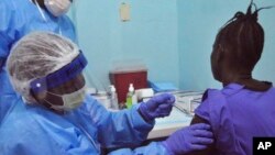 A woman is injected by a health care worker, left, as she takes part in an Ebola virus vaccine trial in Monrovia, Liberia, Monday, Feb. 2, 2015. 