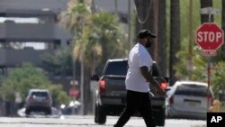 Un peatón cruza una calle mientras olas de calor se elevan desde el pavimento cuando la temperatura alcanza los 104 °F el lunes 17 de junio de 2024 en Phoenix, Arizona.