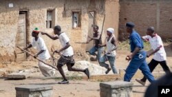 FILE - Members of the Imbonerakure pro-government youth militia chase after opposition protesters, unhindered by police, in the Kinama district of the capital Bujumbura, Burundi, May 25, 2015.