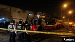 Polisi Peru memeriksa bus yang hangus terbakar di jalanan kota Lima, Peru, March 31, 2019. 