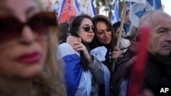 Dos mujeres lloran durante el paso de la comitiva fúnebre de Shiri Bibas y sus dos hijos, Ariel and Kfir, que murieron durante su cautiverio en Gaza, cerca del kibbutz Yad Mordechai, en Israel, el 26 de febrero de 2025. (AP/Maya Alleruzzo)