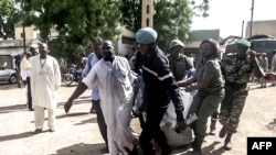FILE - Security forces transport with a blanket the remains of some of the 11 victims of a double blast in the northern Cameroonian city of Maroua, July 22, 2015. 