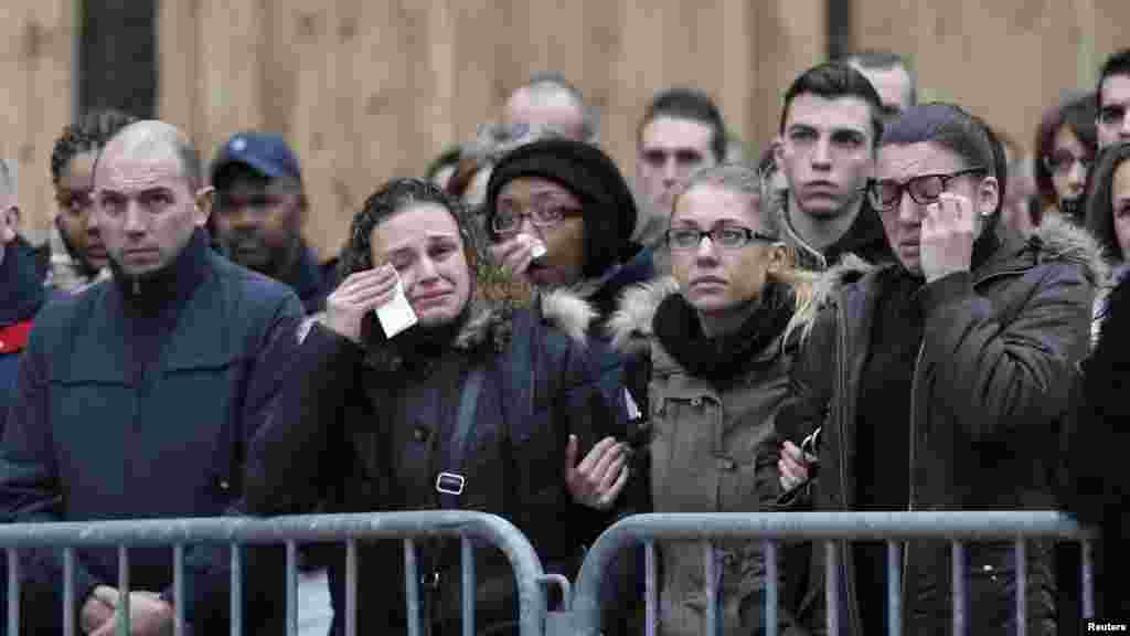 People react as they attend a national tribute for the three officers killed during last week's terrorist attacks, in front of Paris Prefecture, Jan. 13, 2015.