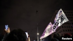 La gente ondea pancartas mientras helicópteros militares vuelan, después de que el presidente surcoreano, Yoon Suk Yeol, declarara la ley marcial, en Seúl, Corea del Sur, el 4 de diciembre de 2024.