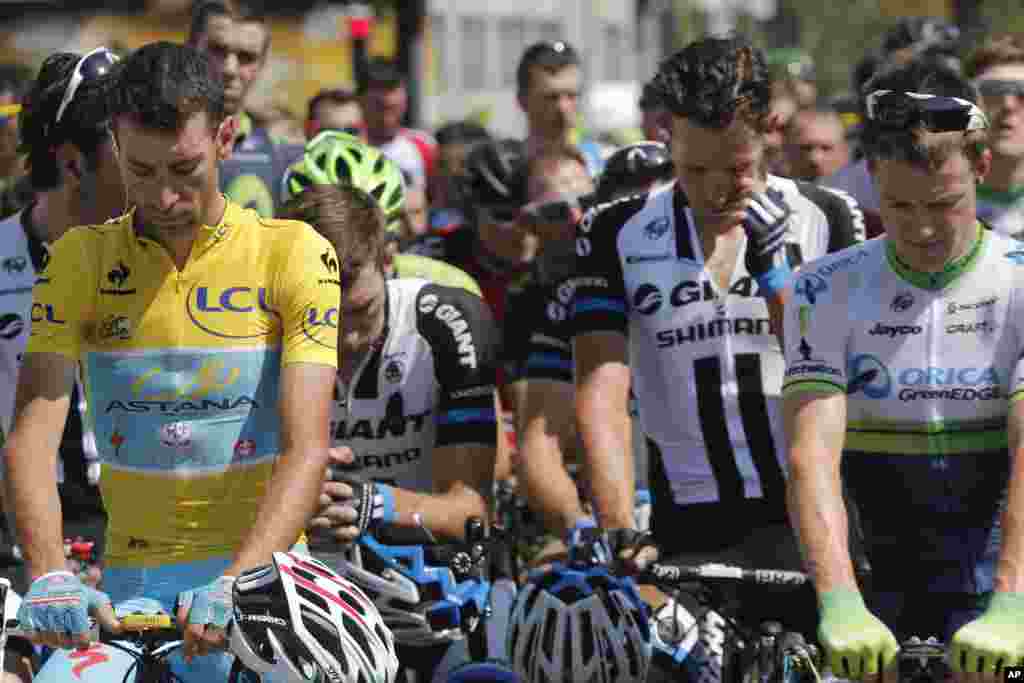 A pack of cyclists, with Italy's Vincenzo Nibali, observe a minute of silence for the victims of the Malaysia Airlines Flight 17 plane crash prior to the start of the thirteenth stage of the Tour de France cycling race, Chamrousee, France, July 18, 2014.