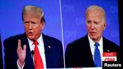 El presidente estadounidense Joe Biden (der) y el ex presidente y candidato presidencial republicano Donald Trump son vistos en un proyector de pantalla durante una celebración de la Coalición Conservadora de Michigan en Novi, Michigan, EEUU, el 27 de junio de 2024.