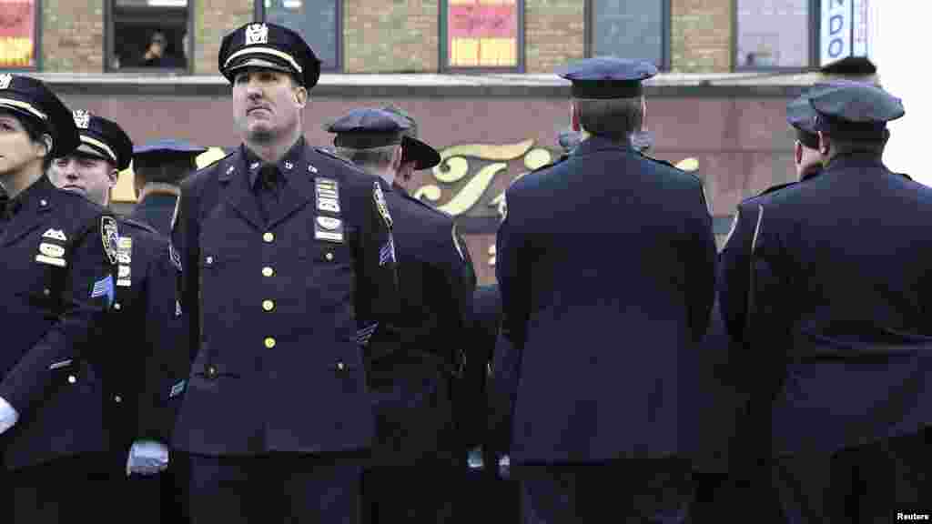 Law enforcement officers stand, with some turning their backs, as New York City Mayor Bill de Blasio speaks on a monitor outside the funeral for NYPD officer Wenjian Liu in the Brooklyn borough of New York, Jan. 4, 2015.