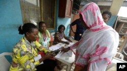 FILE - Semiu Taiwo, right, gets her biometric reading taken during an exercise by the Independent National Electoral Commission to test run new smart card readers.