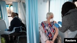 A woman receives a dose of the Oxford-AstraZeneca COVID-19 vaccine inside a mobile vaccination center for the COVID-19, in Thamesmead, London, Feb. 14, 2021. 