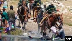 ARCHIVO - Inmigrantes haitianos son impedidos de cruzar hacia la parte estadounidense en Del Río, Texas, en septiembre de 2021.