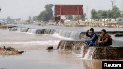 Flood victims sit by a damaged road in Punjab province September 15, 2014. About 150,000 people were still stranded in their homes a week after Indian Kashmir's worst flood in over a century.
