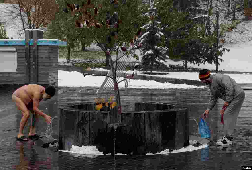 Residents are seen near a city well during the first snowfall, amid Russia's attack on Ukraine, in Kharkiv, Ukraine.