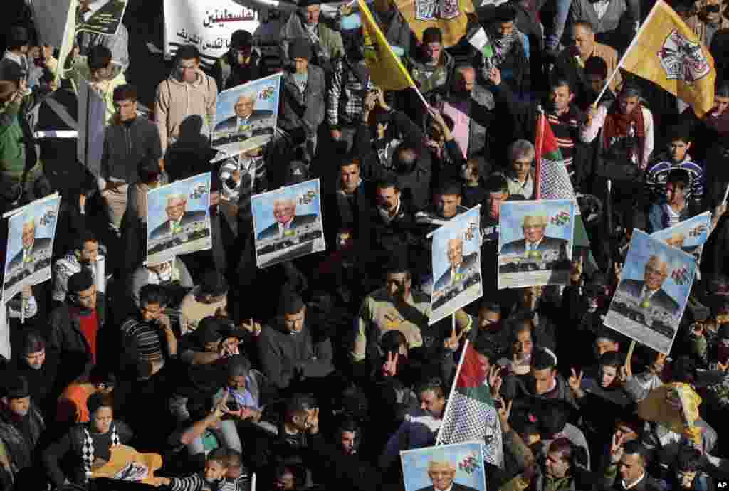 Palestinians hold pictures of President Mahmoud Abbas and wave Fatah flags during a rally supporting the Palestinian U.N. bid for observer state status, Nablus, occupied West Bank, November 29, 2012.