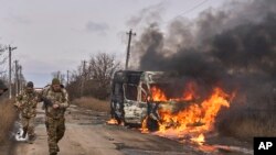 Foto divulgada por los militares ucranianos muestra a soldados ucranianos caminando junto a un autobús en llamas después de un ataque ruso cerca de Bájmut, en la región de Donestk, el 23 de noviembre de 2023.