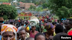 FILE - Refugees from the Democratic Republic of Congo carry their belongings as they walk near the United Nations High Commissioner for Refugees (UNHCR) offices in Kiziba refugee camp in Karongi District, Rwanda, Feb. 21, 2018.