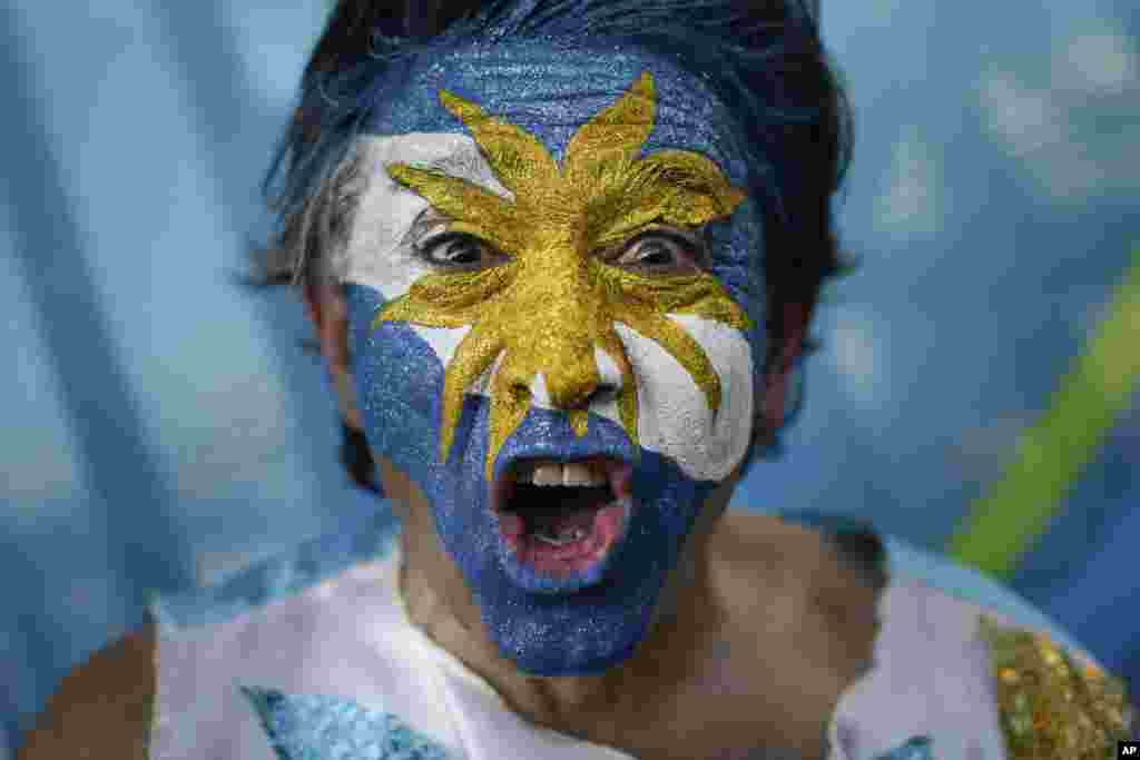 Seorang penggemar tim Argentina dengan riasan muka khas negara tersebut di luar Stadion Maracana sebelum pertandingan antara Argentina dan Bosnia di Rio de Janeiro, Brazil (15/6). Pertandingan dimenangkan Argentina 2-1. (AP/Felipe Dana)