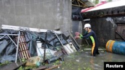A man clears debris near his house flooded by Typhoon Saola in Wujie in Ilan County, Tawian, August 2, 2012.