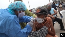 Eighty five-year-old Crisologo Enriquez holds steady as he receives a influenza vaccine during a vaccination campaign and COVID-19 testing operation in the Villa El Salvador neighborhood of Lima, Peru, June 26, 2020.