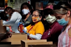 Volunteers prepare donations for delivery to those affected by COVID-19 on tribal lands Thursday, June 25, 2020, in Tempe, Ariz. The resource drive is for Navajo families isolated due to COVID-19.