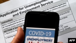 (FILES) In this illustration file photo taken on May 08, 2020, a COVID-19 Unemployment Assistance Updates logo is displayed on a smartphone on top of an application for unemployment benefits, in Arlington, Virginia.