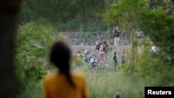 La venezolana Nathaly, de 13 años, observa a agentes de la Patrulla Fronteriza de EEUU devuelven a un grupo de migrantes a México, mientras ella y su familia intentan obtener una cita en la app CBP One desde un campamento improvisado en Matamoros, México, 21 de junio de 2023.