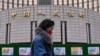 资料照：一名女子走过位于北京的中国人民银行。（2024年2月20日）