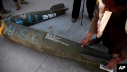 ARCHIVO - En esta foto de archivo del 5 de octubre de 2016, un hombre yemení muestra una bomba de racimo CBU 58A/B de fabricación estadounidense en un recinto policial en Sanaa, Yemen.