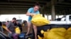 Tiffany Delee tosses a filled sandbag into the back of the family truck, while her husband Mike Delee, left, readies to tie up another bag, in Morgan City, La., July 12, 2019. 