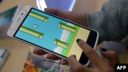 An employee plays the game Flappy Bird at a smartphone store in Hanoi, Feb. 10, 2014. (AFP PHOTO/HOANG DINH Nam)