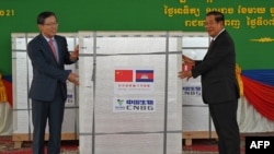 China's ambassador to Cambodia Wang Wentian (L) hands over a shipment of Sinopharm Covid-19 coronavirus vaccine to Cambodian Prime Minister Hun Sen (R) during a ceremony at Phnom Penh International Airport in Phnom Penh on February 7, 2021. (Photo by TANG CHHIN Sothy / AFP) 