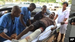 FILE - An injured man is helped at a private hospital after an alleged assault by a group of uniformed soldiers in Harare, Zimbabwe, Thursday, Jan. 17, 2019.