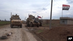 In this frame grab from video, an American military convoy is seen in the village of Khirbet Ammu, east of Qamishli city, Syria, Wednesday, Feb. 12, 2020. Syrian media and activists say a Syrian was killed and another wounded in a rare clash between…