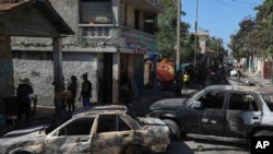 Los residentes pasan junto a vehículos incendiados por bandas armadas en el barrio de Poste Marchand de Puerto Príncipe, Haití, el martes 10 de diciembre de 2024. 