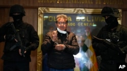 ARCHIVO - La policía escolta al ex coronel de policía Maximiliano Dávila, centro, mientras fue presentado a los medios en una oficina del Comando de la Policía Boliviana en La Paz, Bolivia, el 23 de enero de 2022. AP