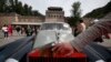 FILE - A man places his hand near the logo of a Rolls Royce at the Shuiguan Great Wall on the outskirts of Beijing, China, Sept. 18, 2011. A new law now tries to coordinate charitable giving by country's richest.