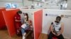 FILE - A young woman is administered her first dose of a COVID-19 vaccine, at a vaccination site set up in a shopping mall on the outskirts of Rome, Italy, June 1, 2021. 