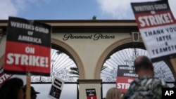 ARCHIVO - Manifestantes caminan con carteles durante una manifestación frente al estudio Paramount Pictures en Los Ángeles, el jueves 21 de septiembre de 2023.