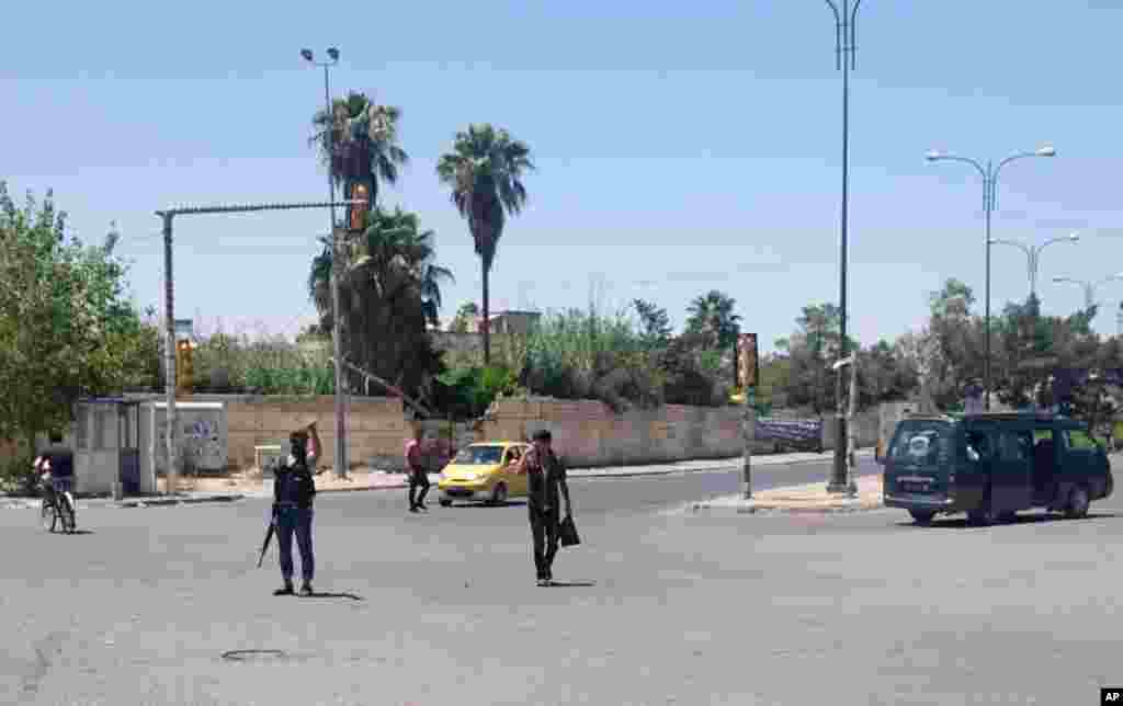 "Iroq va Shom islomiy davlati" guruhi jangarisi ko'chada mashinalar harakatini tartibga solmoqda, Mosul, Iroq, 22-iyun, 2014-yil. 