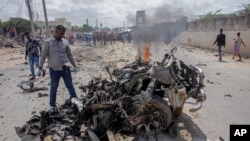 Les forces de sécurité et les civils se rassemblent près des décombres après un attentat suicide à la voiture piégée qui visait le commissaire de police de la ville de Mogadiscio, en Somalie, le 10 juillet 2021.
