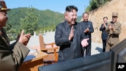 Gambar cuplikan video dari siaran berita yang dipancarkan Korea Utar menunjukkan apa yang disampaikan kepada pemimpin Korea Utara, Kim Jong Un, tengah (KRT via AP Video)