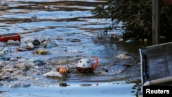 Petugas SAR berenang sambil memeriksa kawasan pemukiman di Kawasaki, Tokyo, yang terendam banjir akibat Taifun Hagibis, 13 Oktober 2019. (Foto: Reuters)